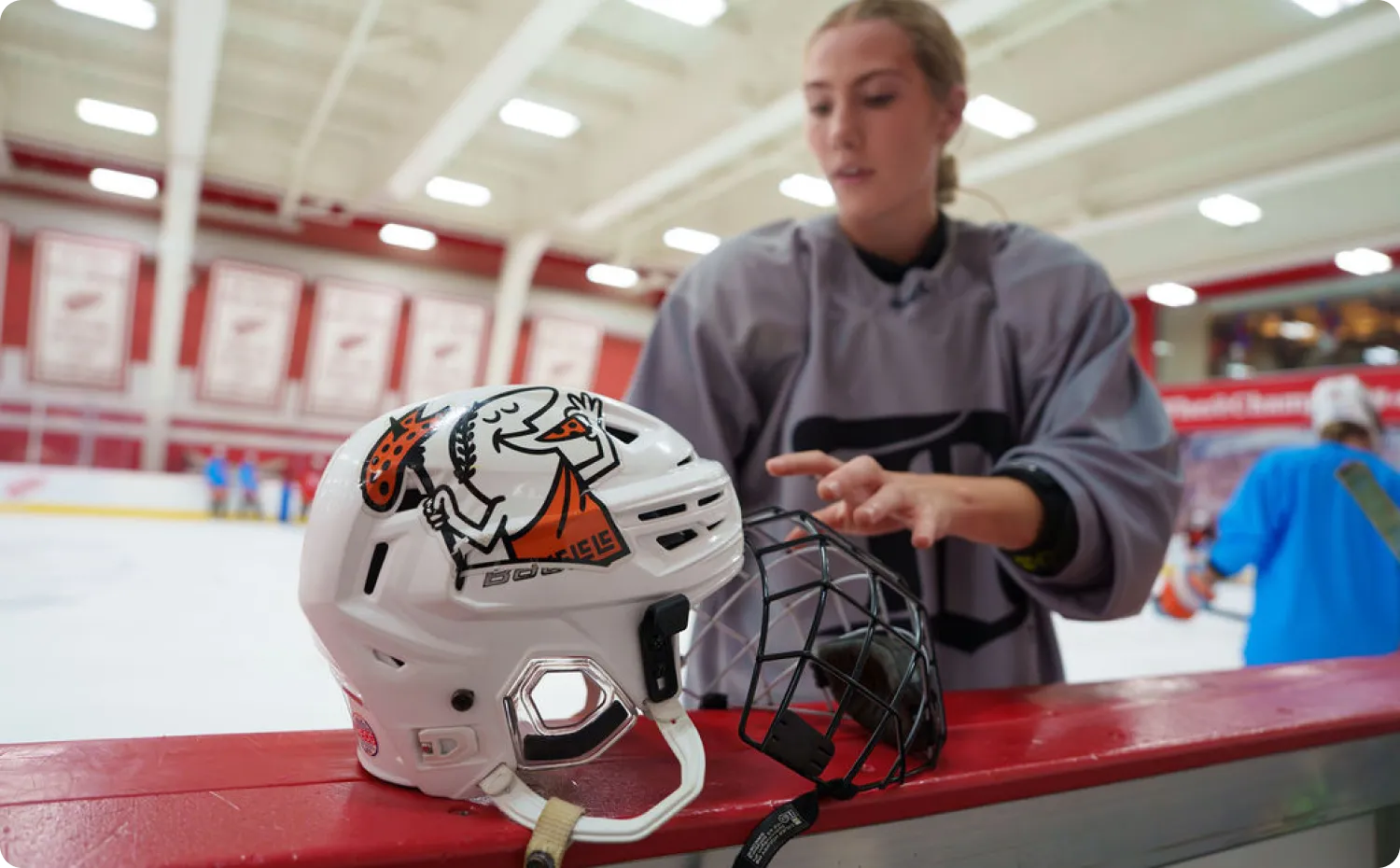 Little Caesars player preparing gear at the rink